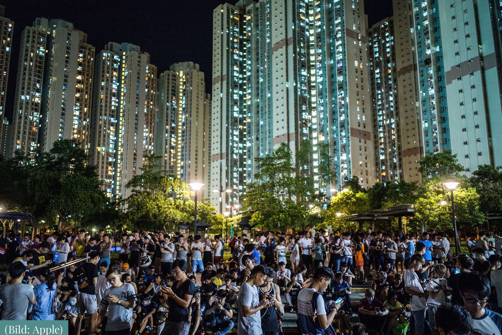 Large crowd of people in front of illuminated skyscrapers at night