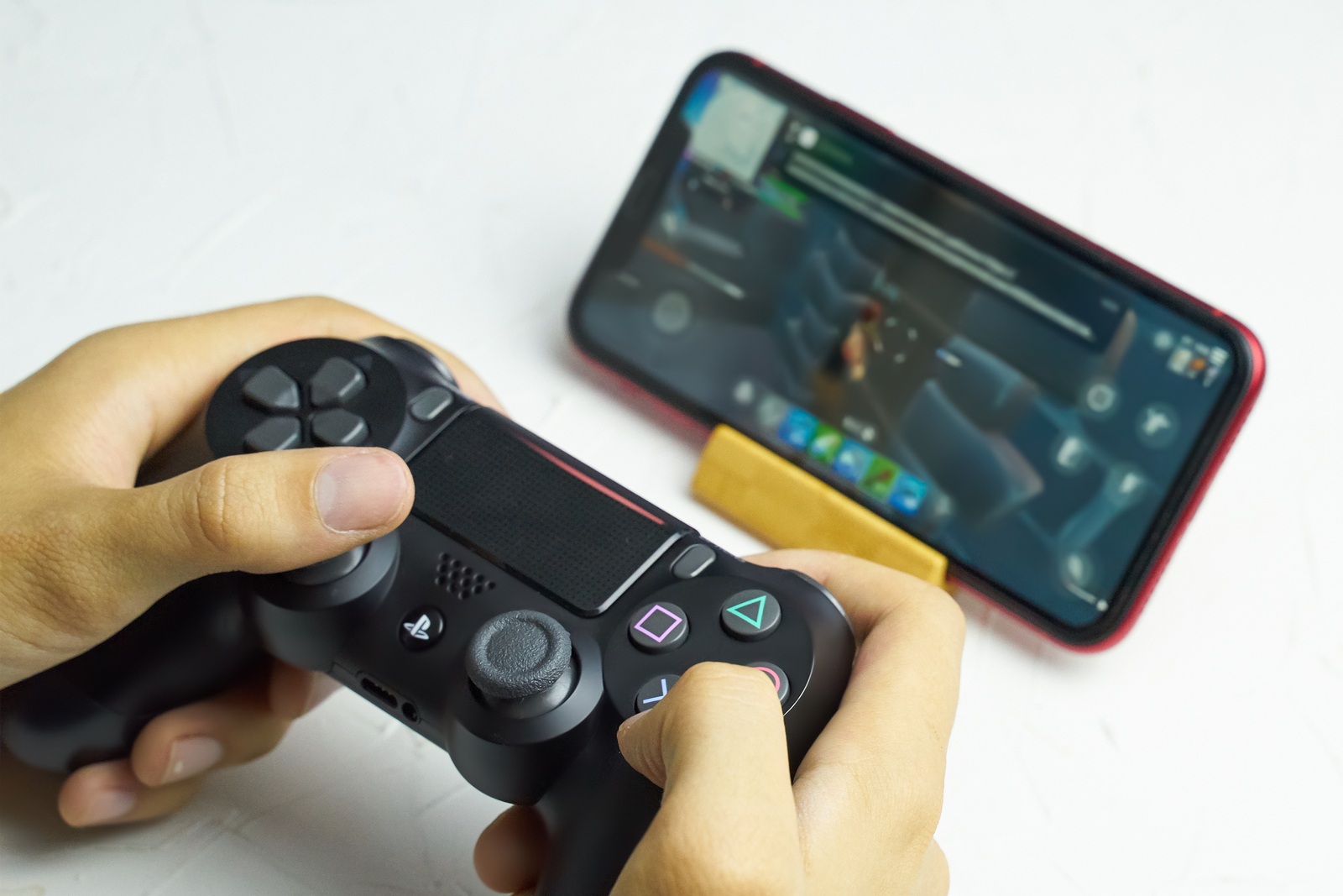 Bishkek, Kyrgyzstan - June 06, 2019: Man playing games on Apple arcade subscription system on iOS 13 with Sony Dualshock gamepad