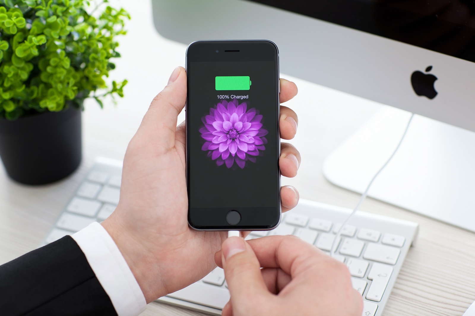 Alushta Russia - November 3 2014: Man holding an iPhone 6 Space Gray with battery icon on the screen. iPhone 6 was created and developed by the Apple inc.