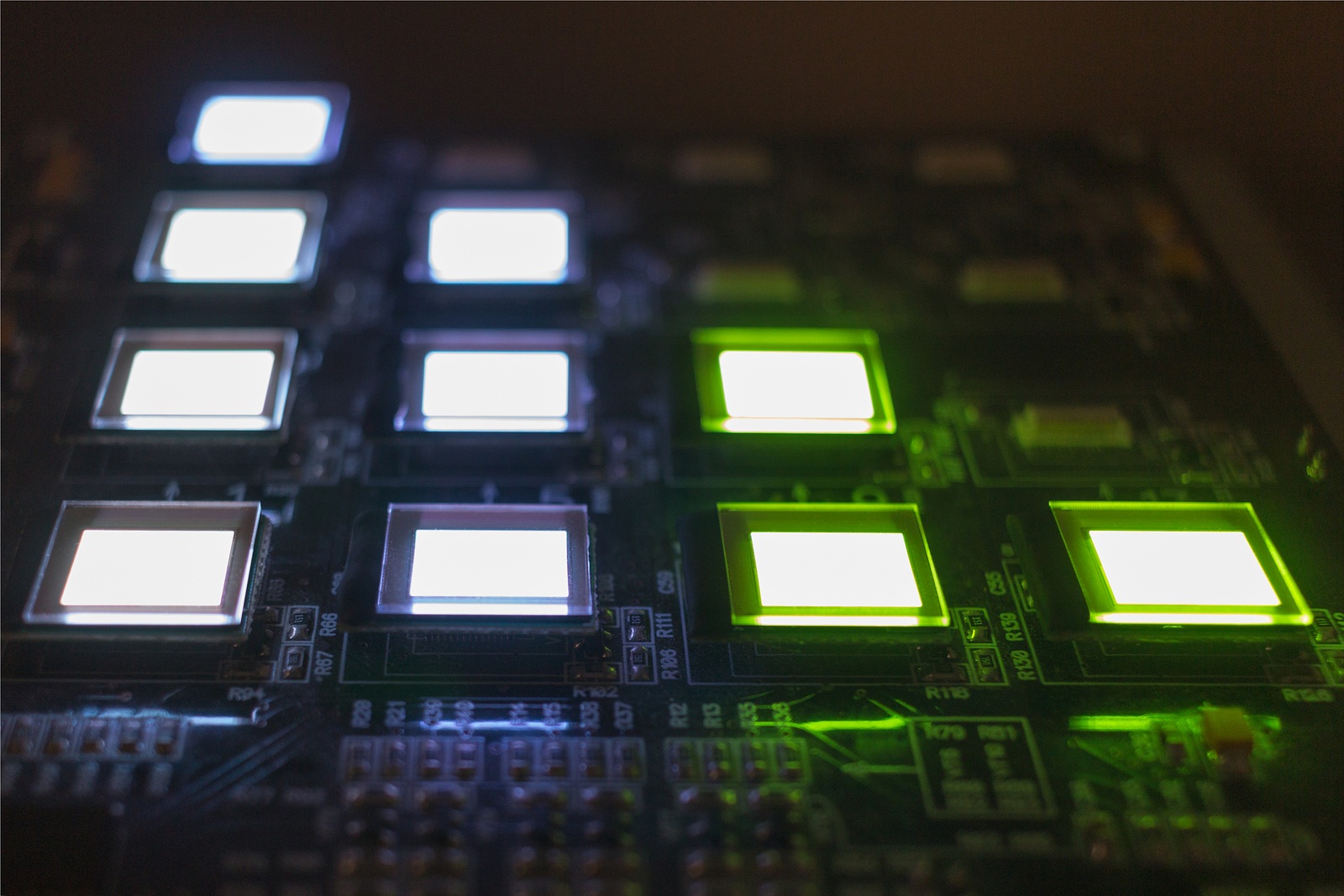 The process of checking several OLED displays on the test station. Displays glow brightly of green and white color close up.