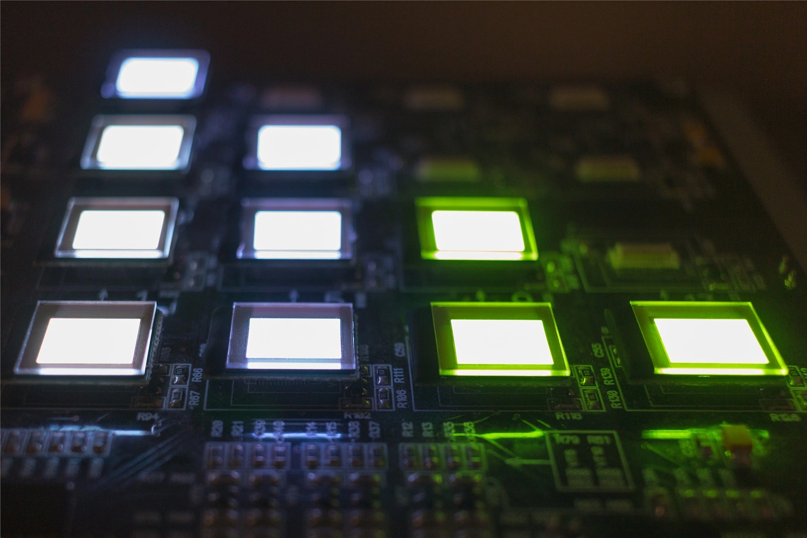The process of checking several OLED displays on the test station. Displays glow brightly of green and white color close up.