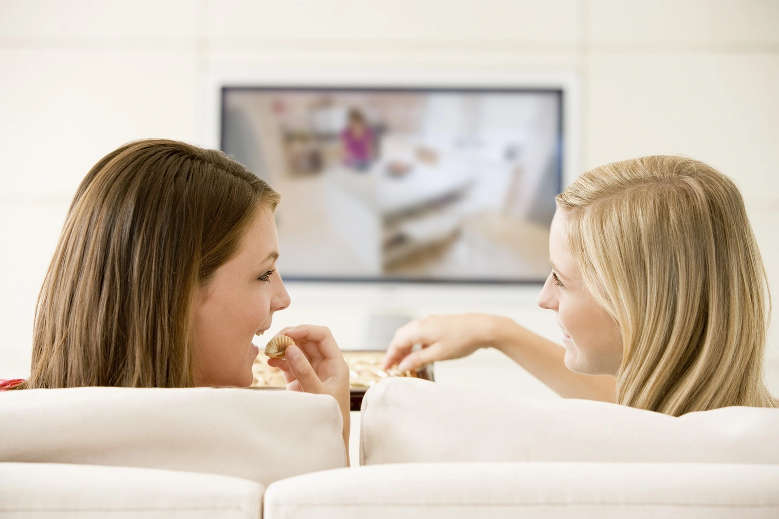 Teen girls relaxing at home on sofa watching TV