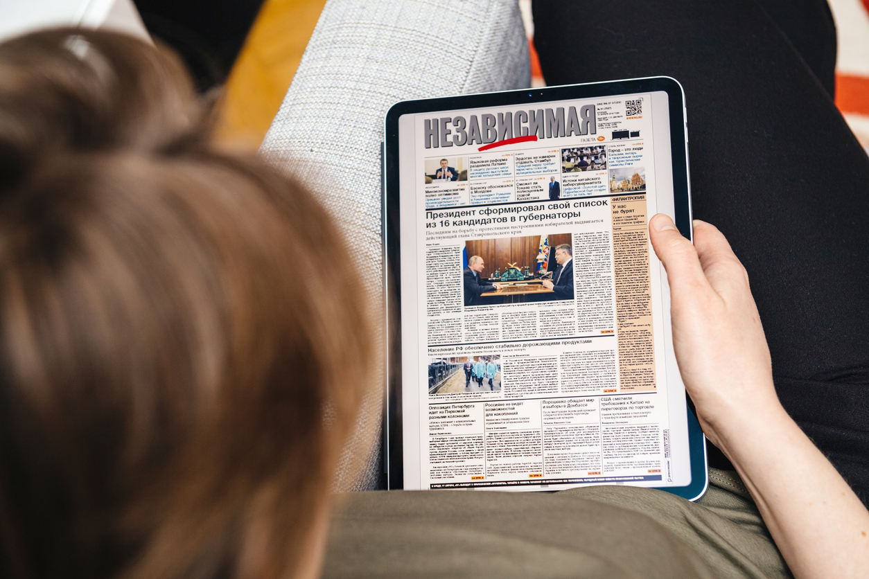 Paris, France - Apr 15, 2019: Woman reading on iPad Pro Apple News Plus Nezavisimaya Gazeta digital newspaper featuring breaking about 16 governors list made by Vladimir Putin Russian President