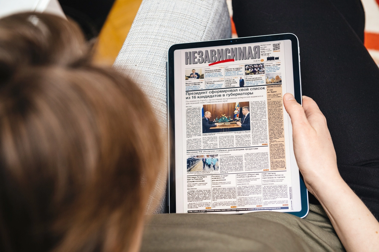 Paris, France - Apr 15, 2019: Woman reading on iPad Pro Apple News Plus Nezavisimaya Gazeta digital newspaper featuring breaking about 16 governors list made by Vladimir Putin Russian President