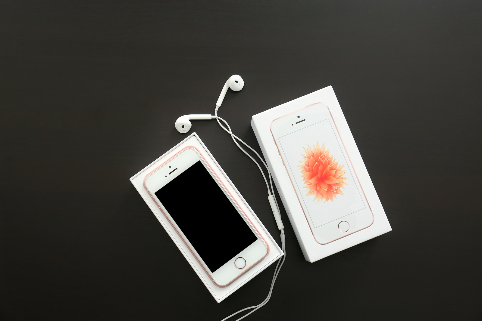 KIEV, UKRAINE - OCTOBER 17, 2017: Rose gold iPhone SE with earphones and box on black table
