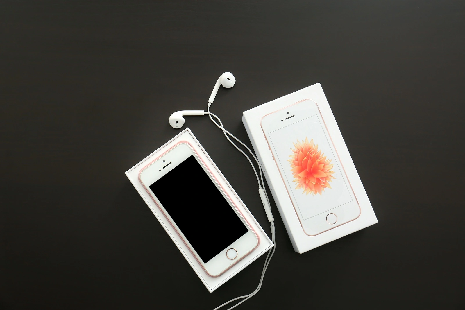 KIEV, UKRAINE - OCTOBER 17, 2017: Rose gold iPhone SE with earphones and box on black table