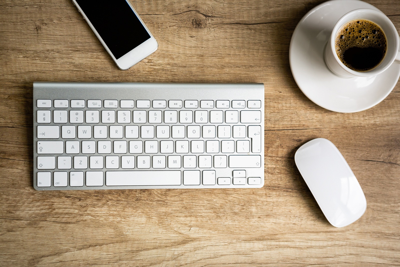 Modern workspace, keyboard and coffee cup over wooden table