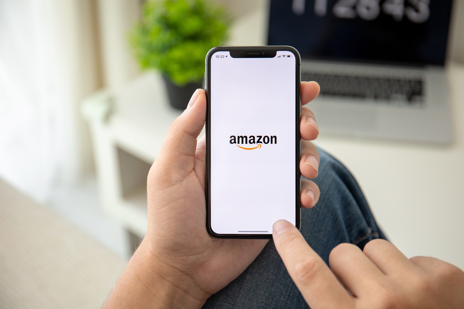 Alushta, Russia - July 29, 2018: Man holding iPhone X with Internet shopping service Amazon on the screen. iPhone ten was created and developed by the Apple inc.