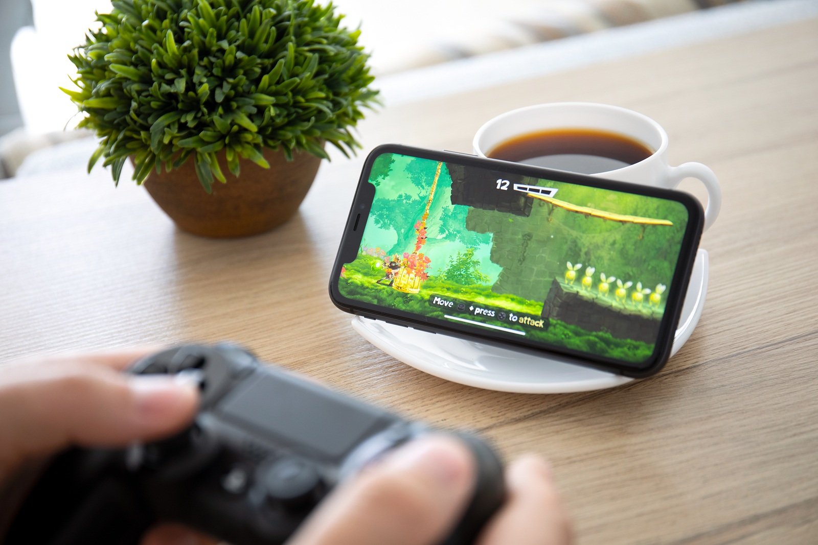 Anapa, Russia - October 2, 2019: Man hand holding Dualshock 4 play game Rayman Adventures in the screen on iPhone 11. Games Rayman Adventures was developer by the Ubisoft.