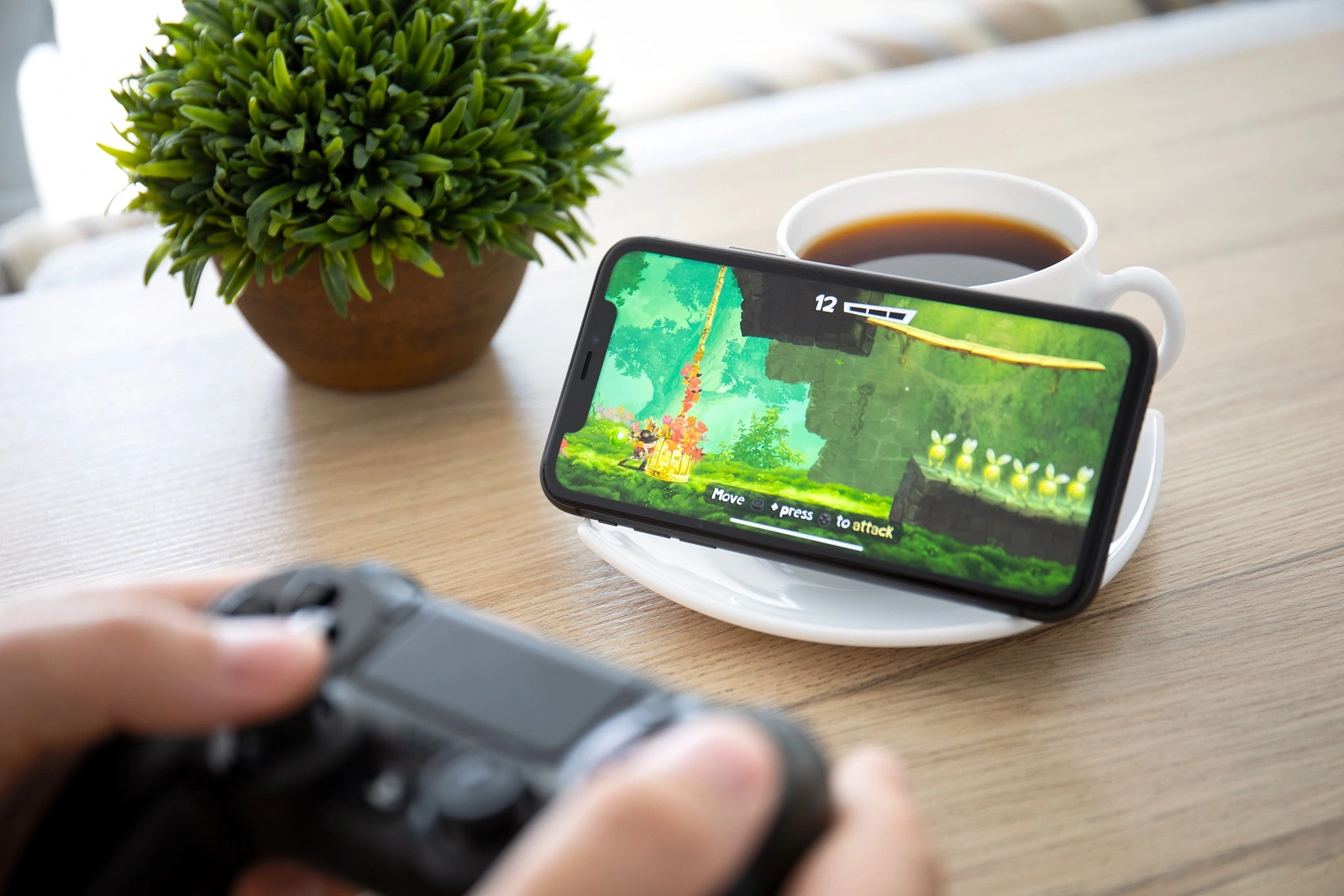 Anapa, Russia - October 2, 2019: Man hand holding Dualshock 4 play game Rayman Adventures in the screen on iPhone 11. Games Rayman Adventures was developer by the Ubisoft.