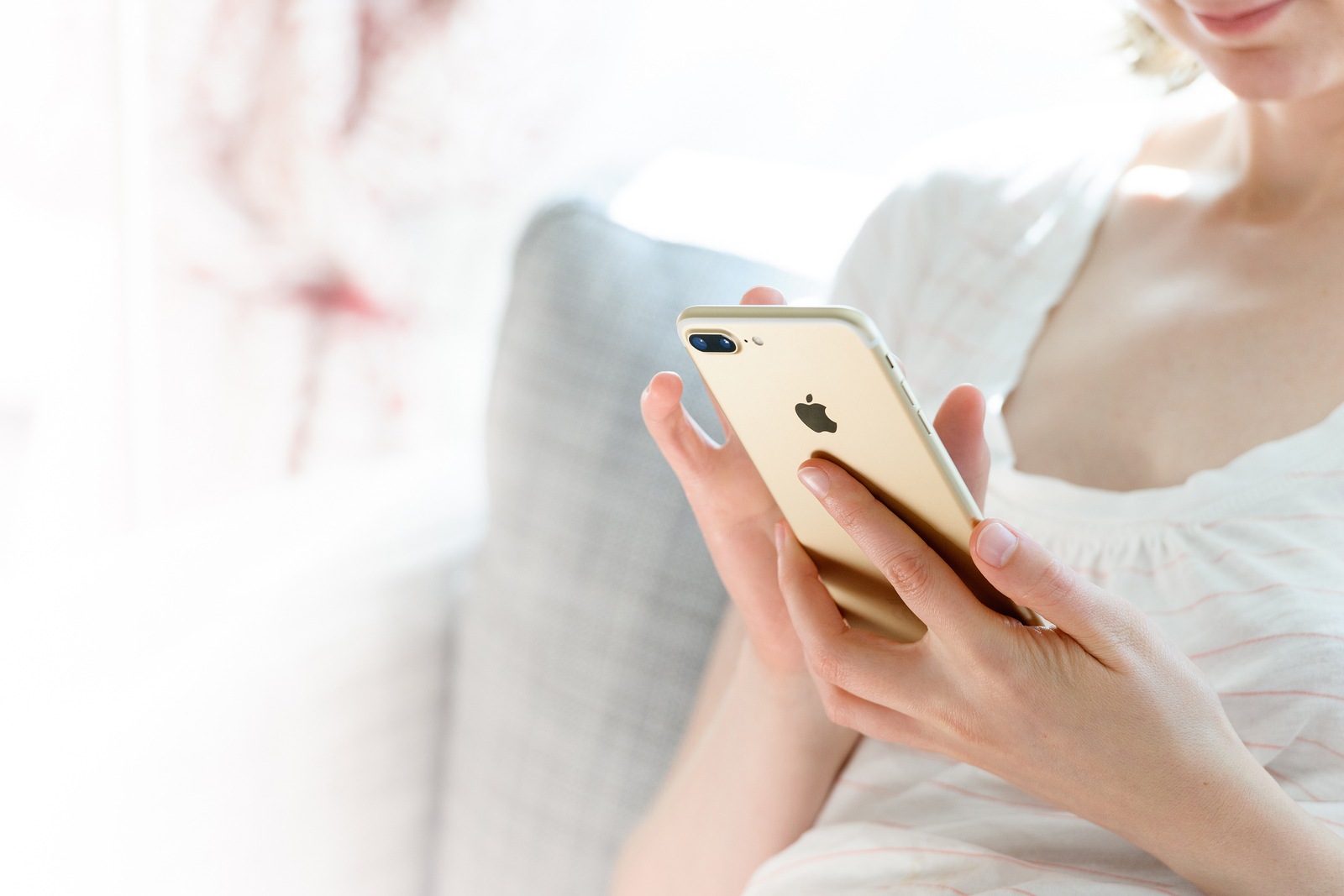 PARIS FRANCE - SEP 29 2016: New Apple iPhone 7 plus display in woman's hands - she is testing the camera and overall presentation sitting on the couch in home environment. New Apple iPhone tends to become one of the most popular smartphones in the world