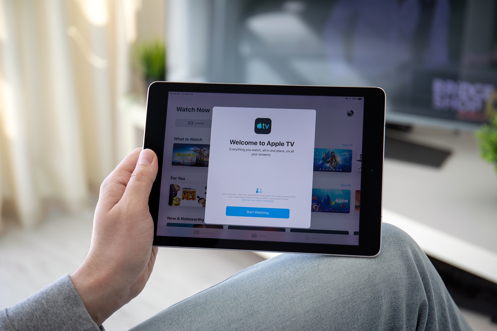 Anapa, Russia - March 29, 2019: Man holding iPad Pro with Apple TV app provides streaming movies and cable channel on the screen.