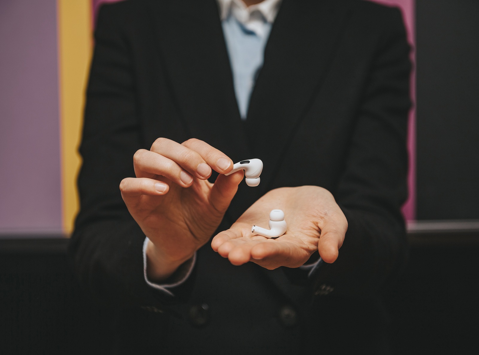 Paris, France - Oct 30, 2019: Woman wearing business suit presenting delicate tiny new Apple Computers AirPods Pro headphones with Active Noise Cancellation for immersive sound
