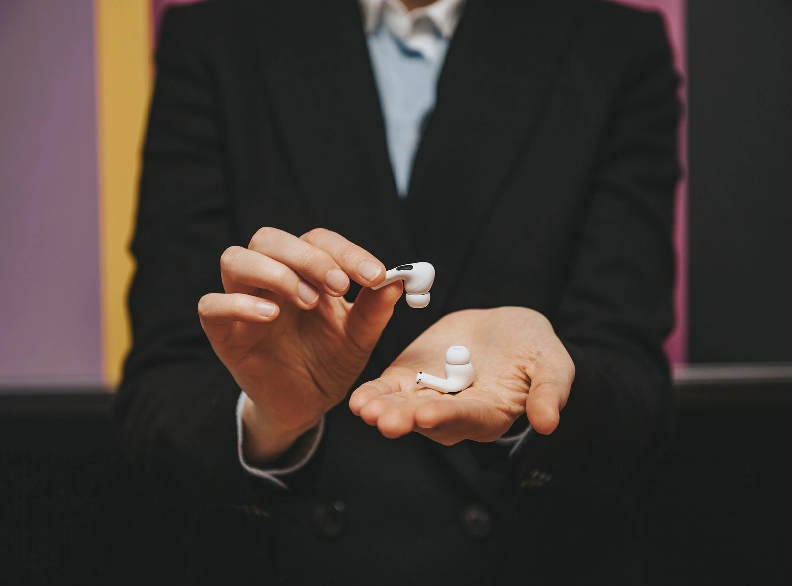 Paris, France - Oct 30, 2019: Woman wearing business suit presenting delicate tiny new Apple Computers AirPods Pro headphones with Active Noise Cancellation for immersive sound