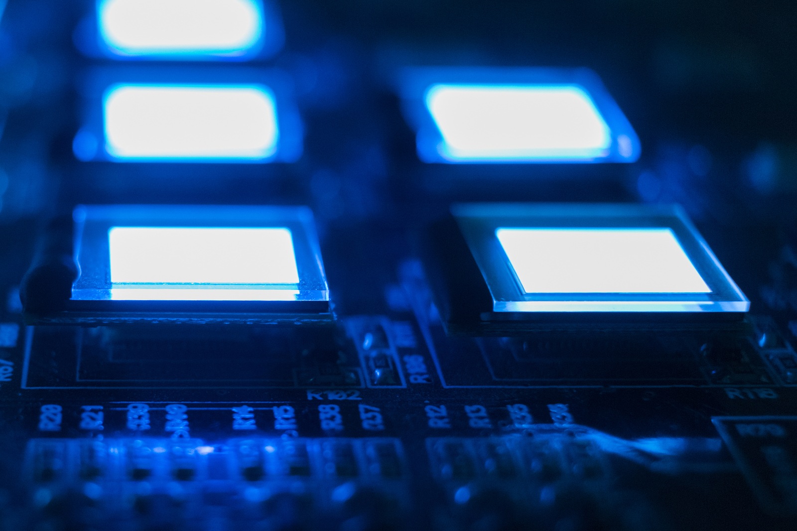 The process of checking several OLED displays on the test station. Displays glow brightly blue color close up.