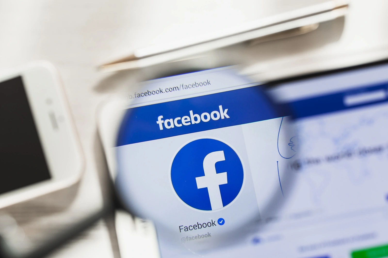 California, USA - March 7, 2019: Facebook, social network official website homepage under magnifying glass. Concept Facebook, social network logo visible on smartphone, tablet screen