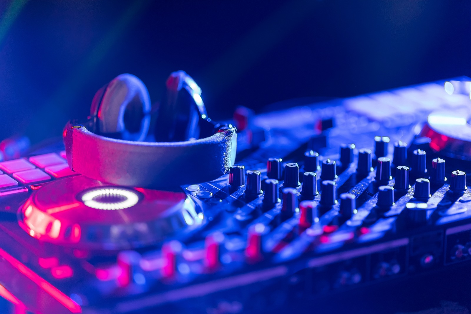 In selective focus of Pro dj controller.The DJ console cd mp4 deejay mixing desk Ibiza house music party in nightclub with colored disco lights.