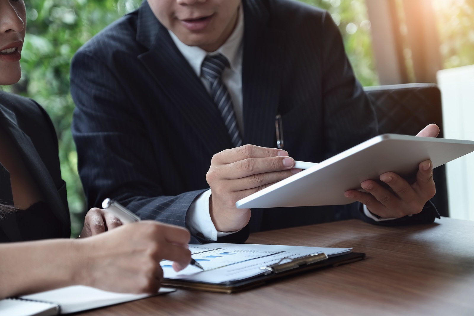 A male business consultant describes a marketing plan to set business strategies for women business owners witch using ipad. business planning and business research concept.