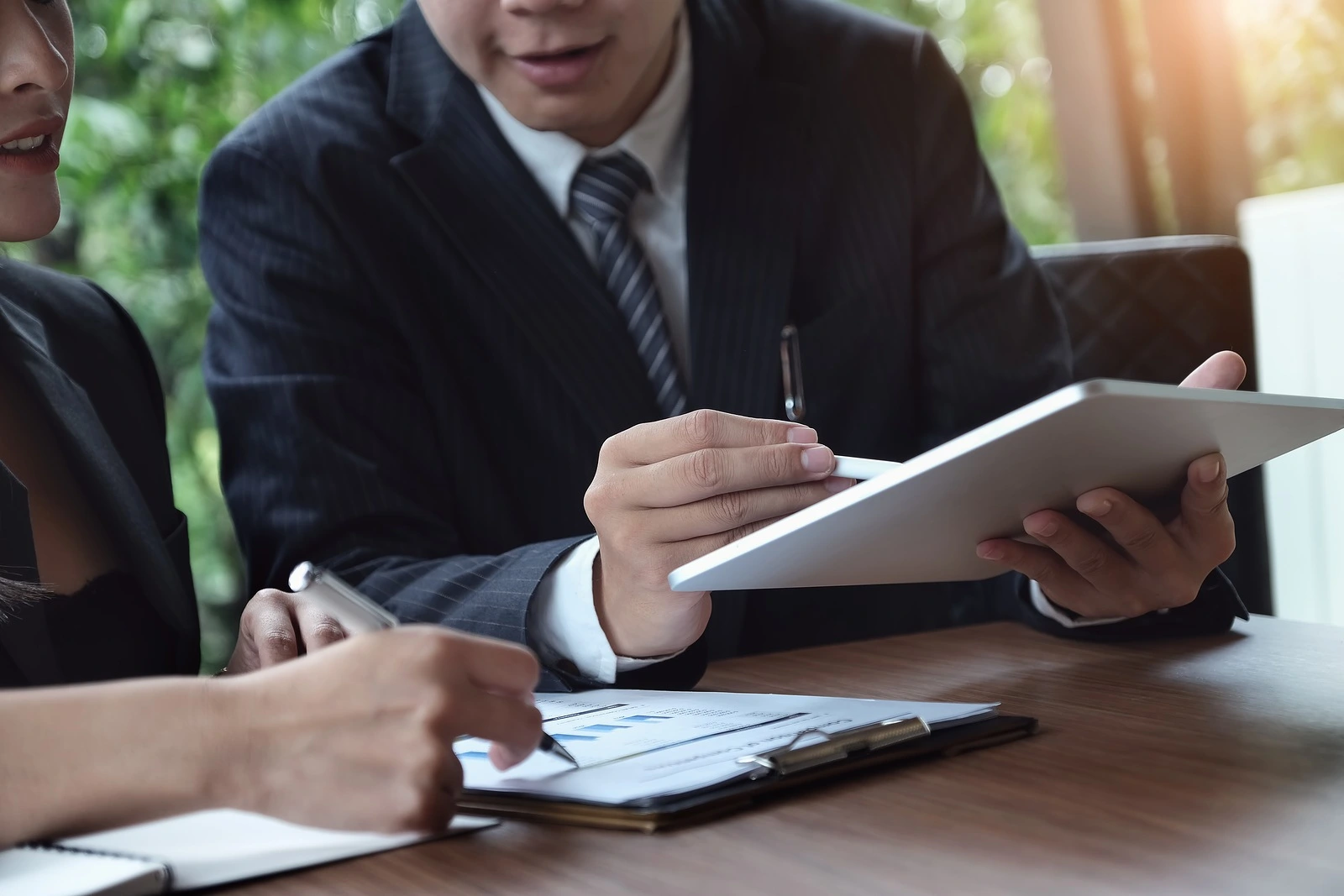A male business consultant describes a marketing plan to set business strategies for women business owners witch using ipad. business planning and business research concept.