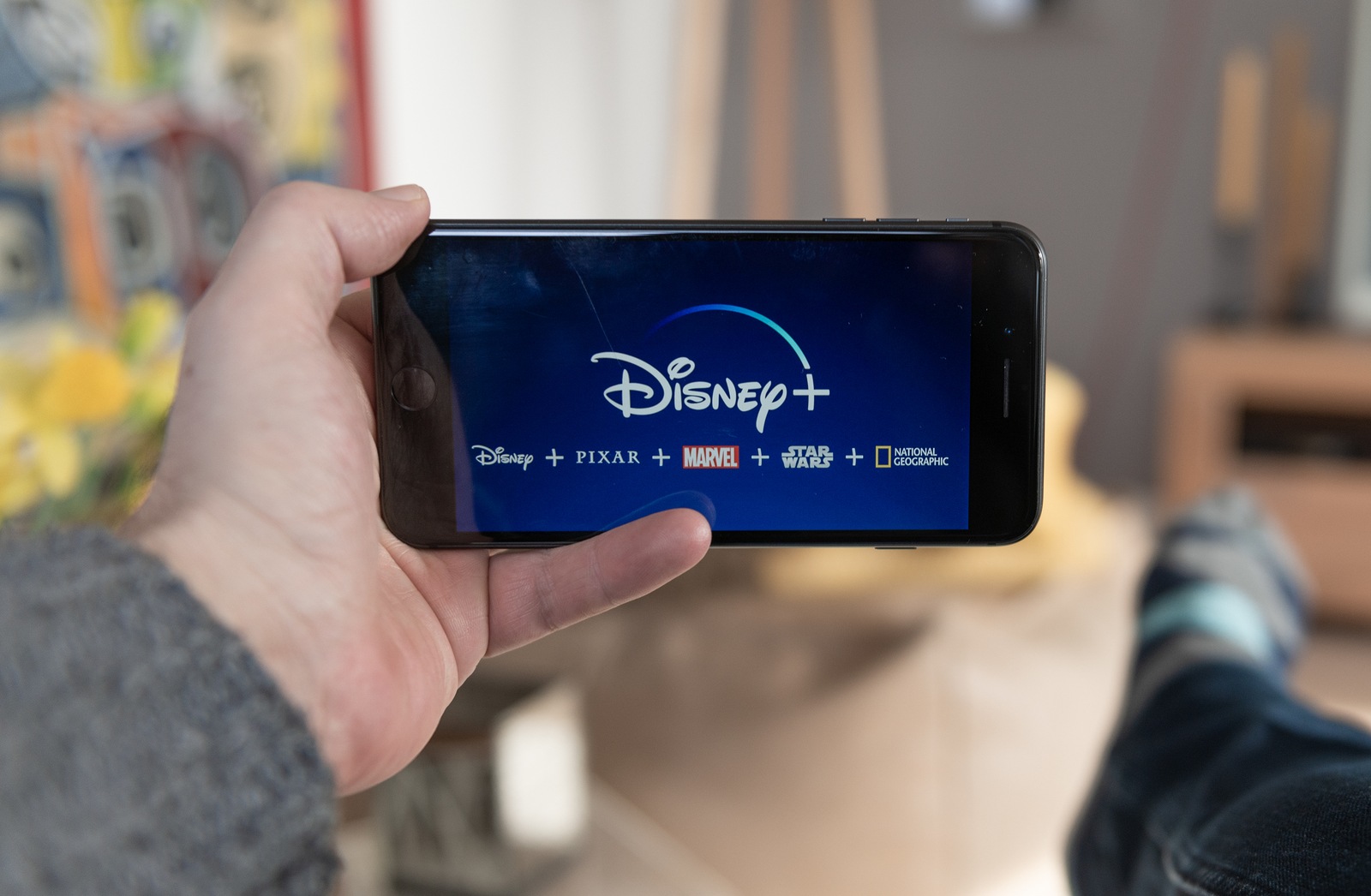 Amsterdam, The Netherlands, 02/03/2020, Disney+ start screen on mobile phone. Disney+ online video, content streaming subscription service. Man holds his smartphone up and looks at Disney Plus