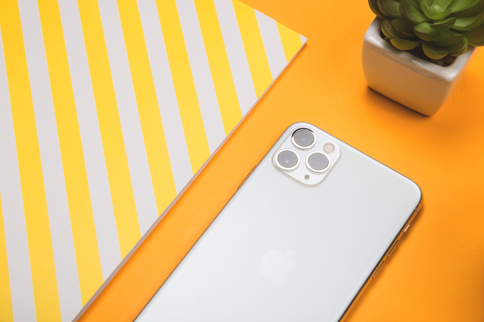 Kiev, Ukraine - November 13, 2019: New white smartphone Apple Computers iPhone 11 Pro and 11 Pro Max smartphone with three cameras or lenses on a yellow desktop.