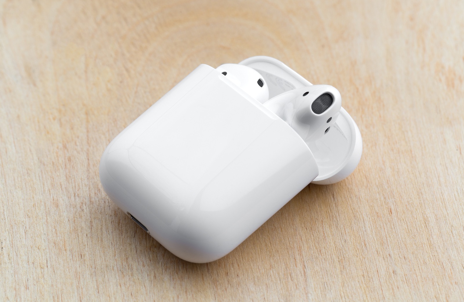 Rostov-on-Don, Russia - December 2018. Apple Airpods in a charging case on a wooden surface. New Airpods in a charging case close-up on a wooden table.