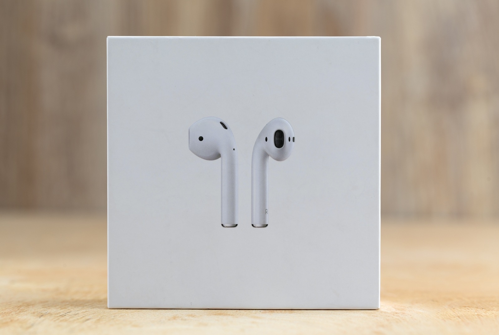 Rostov-on-Don, Russia - December 2018. Apple Airpods in a box on a wooden surface. New Airpods sealed in a box close-up on a wooden table.