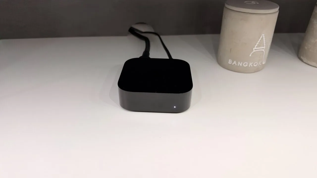 Apple TV or smart TV: connected Apple TV 4K with its status light on and cables attached, sitting on a white shelf