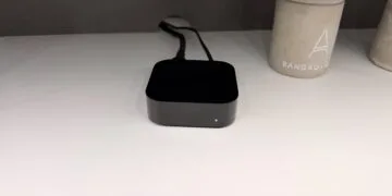 Apple TV or smart TV: connected Apple TV 4K with its status light on and cables attached, sitting on a white shelf