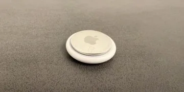 Apple AI pin: an AirTag on a grey surface used as a size comparison
