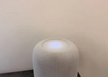 HomePod plays music on its own: white HomePod with its touch surface lit up in front of a light wall