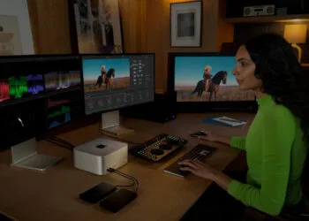 Workstation with Mac Studio and three external displays, a person editing video at keyboard and color grading panel