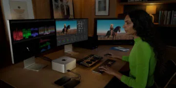 Workstation with Mac Studio and three external displays, a person editing video at keyboard and color grading panel