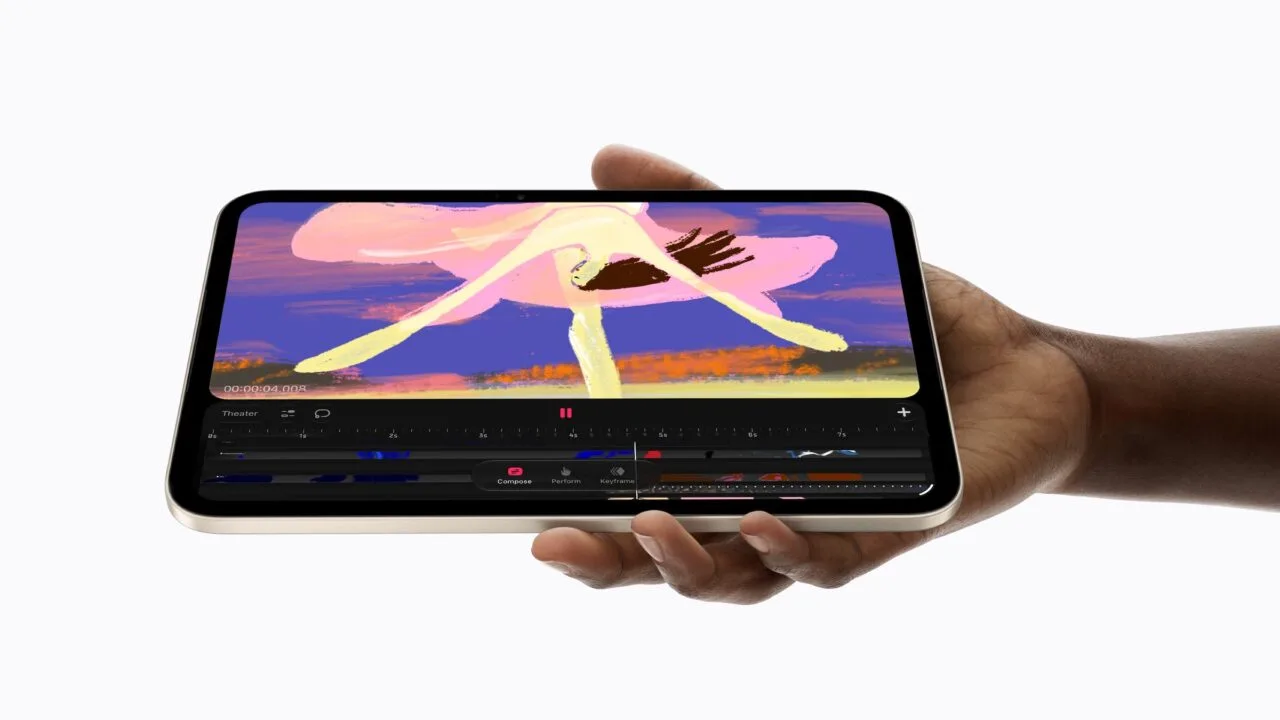 The iPad mini A20 Pro in starlight held sideways in one hand, showing an animation app