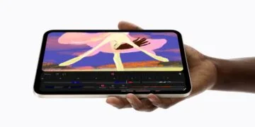 The iPad mini A20 Pro in starlight held sideways in one hand, showing an animation app