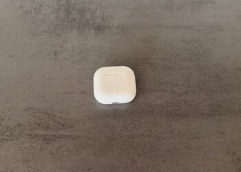 Closed AirPods 4 charging case on a dark surface, whose successor AirPods 5 appears as a codename in the macOS update