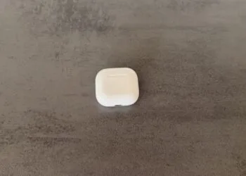 Closed AirPods 4 charging case on a dark surface, whose successor AirPods 5 appears as a codename in the macOS update