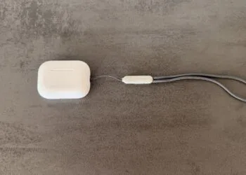 AirPods Pro 3 charging case with grey lanyard on a concrete surface, model without cameras