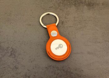 AirTag 2 in a fuchsia FineWoven key ring on a dark surface, the type of tracker used in AirTag stalking