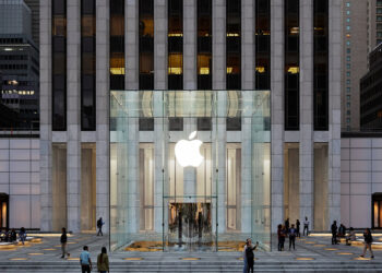 Symbolic image for Apple government affairs: the glass entrance cube of the Apple Store on Fifth Avenue in New York at dusk