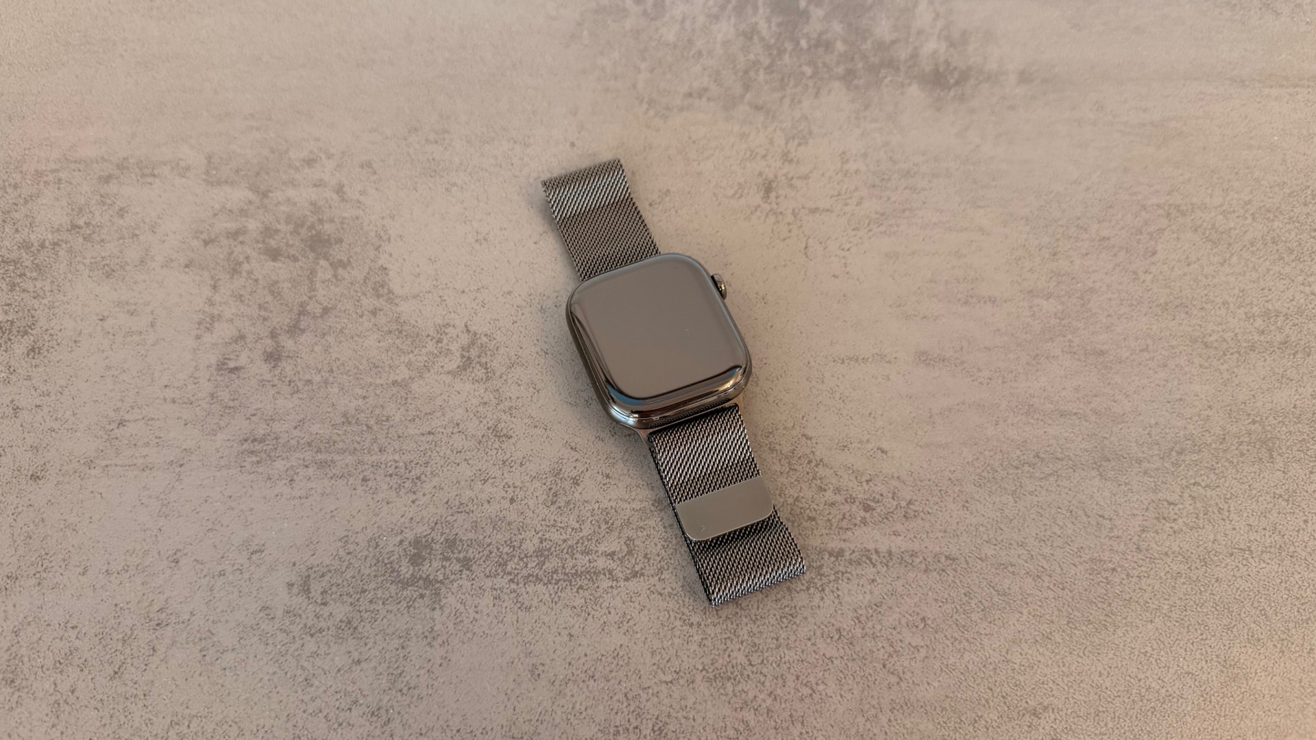 Apple Watch Series 11 in slate titanium with a Milanese loop, whose rectangular display Apple could replace with new shapes according to the report