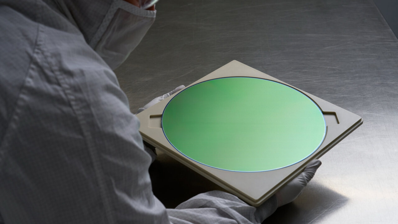 Worker in a cleanroom suit holding a semiconductor wafer of the kind TSMC also produces for iPhone 18 Pro chips