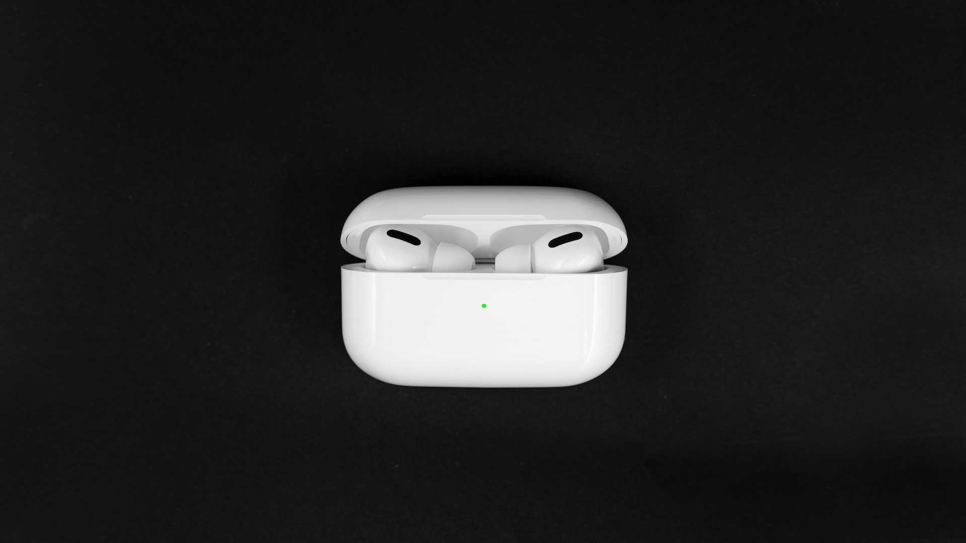 AirPods Pro with wireless charging case against a black background
