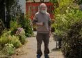 Small Prophets on Apple TV: a bearded man holding a mug stands in an overgrown driveway