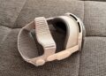 Apple Vision Pro with light Dual Knit Band resting on its side on a grey woven sofa surface