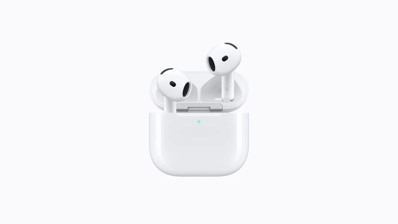 AirPods 5 in the open charging case with a green charge indicator on a light background