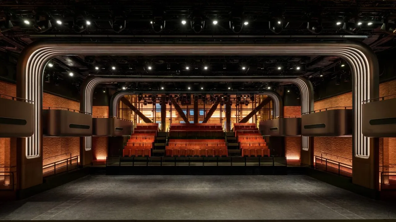 Apple Music Hall in Battersea Power Station: view across the open floor to red seating tiers, balconies and brick walls, with a glass wall behind