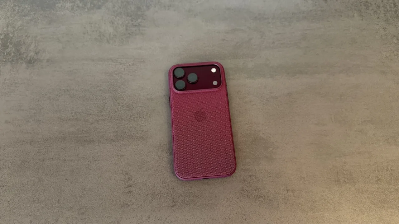 Back of an iPhone 18 Pro Max in a burgundy case on a grey surface, covered by the renewed Apple Qualcomm patent license