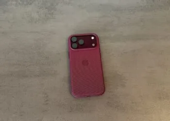 Back of an iPhone 18 Pro Max in a burgundy case on a grey surface, covered by the renewed Apple Qualcomm patent license