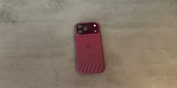 Back of an iPhone 18 Pro Max in a burgundy case on a grey surface, covered by the renewed Apple Qualcomm patent license